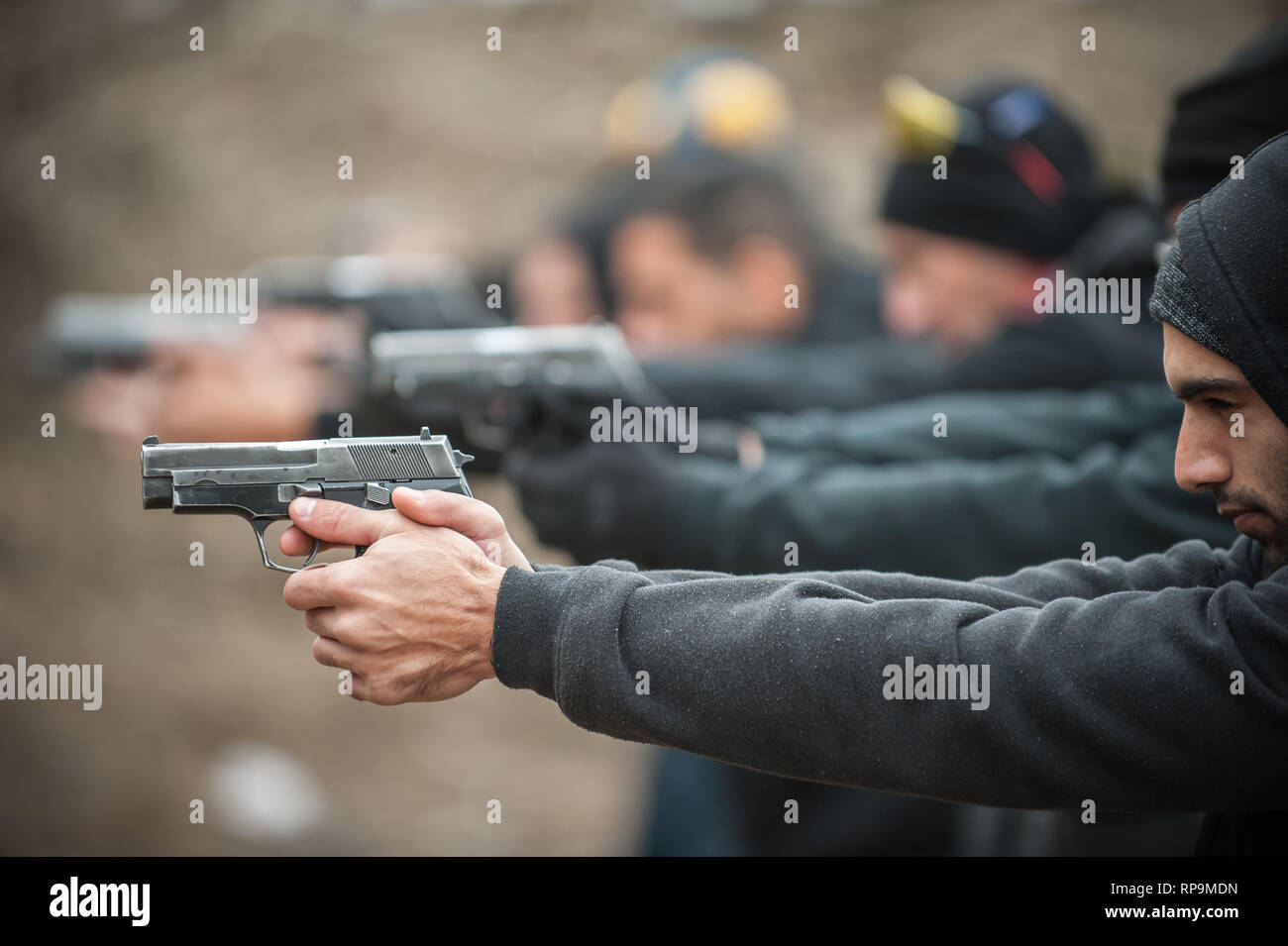 Gruppo di pratica civile pistola spara sul bersaglio all'aperto sul poligono di tiro. Team civili addestramento alle armi Foto Stock