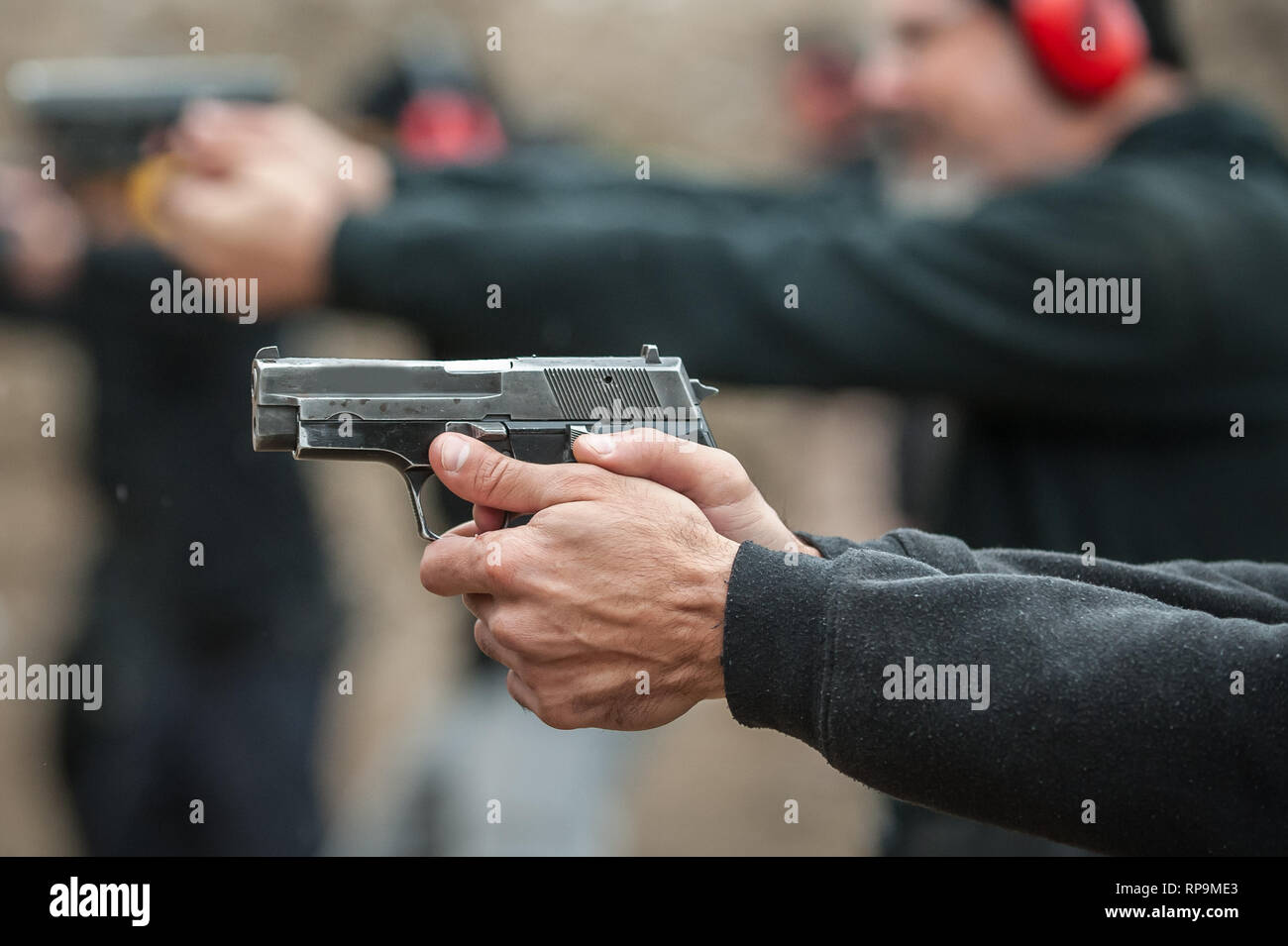 Gruppo di pratica civile pistola spara sul bersaglio all'aperto sul poligono di tiro. Team civili addestramento alle armi Foto Stock