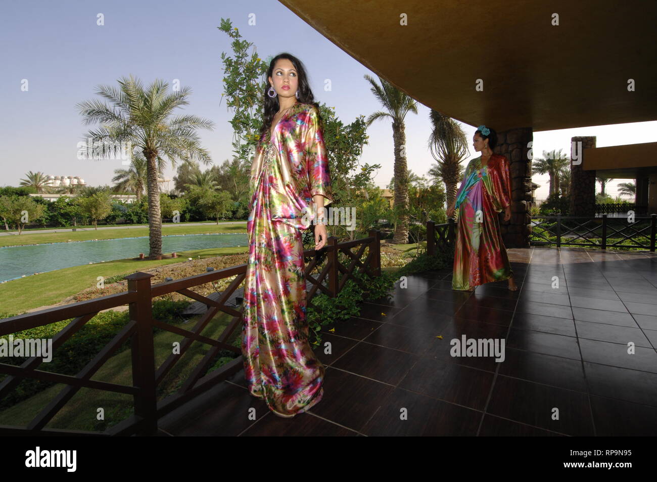 Le ragazze di nazionalità asiatica vestita in bright abiti estivi sono a piedi nel giardino estivo di una casa di campagna. Foto Stock