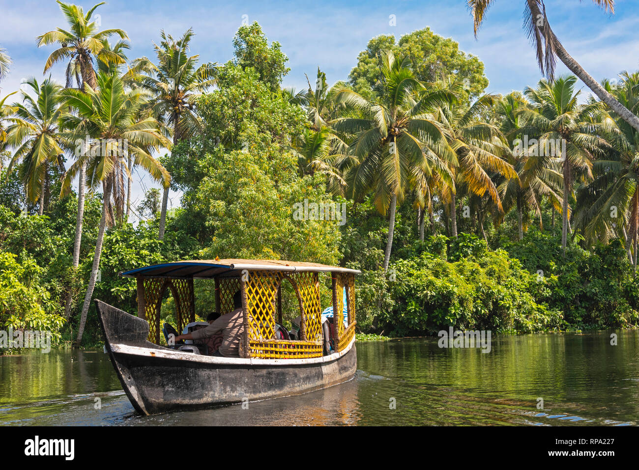 Una giornata tipica barca galleggianti in Kerala backwaters in una giornata di sole con cielo blu e palme. Foto Stock