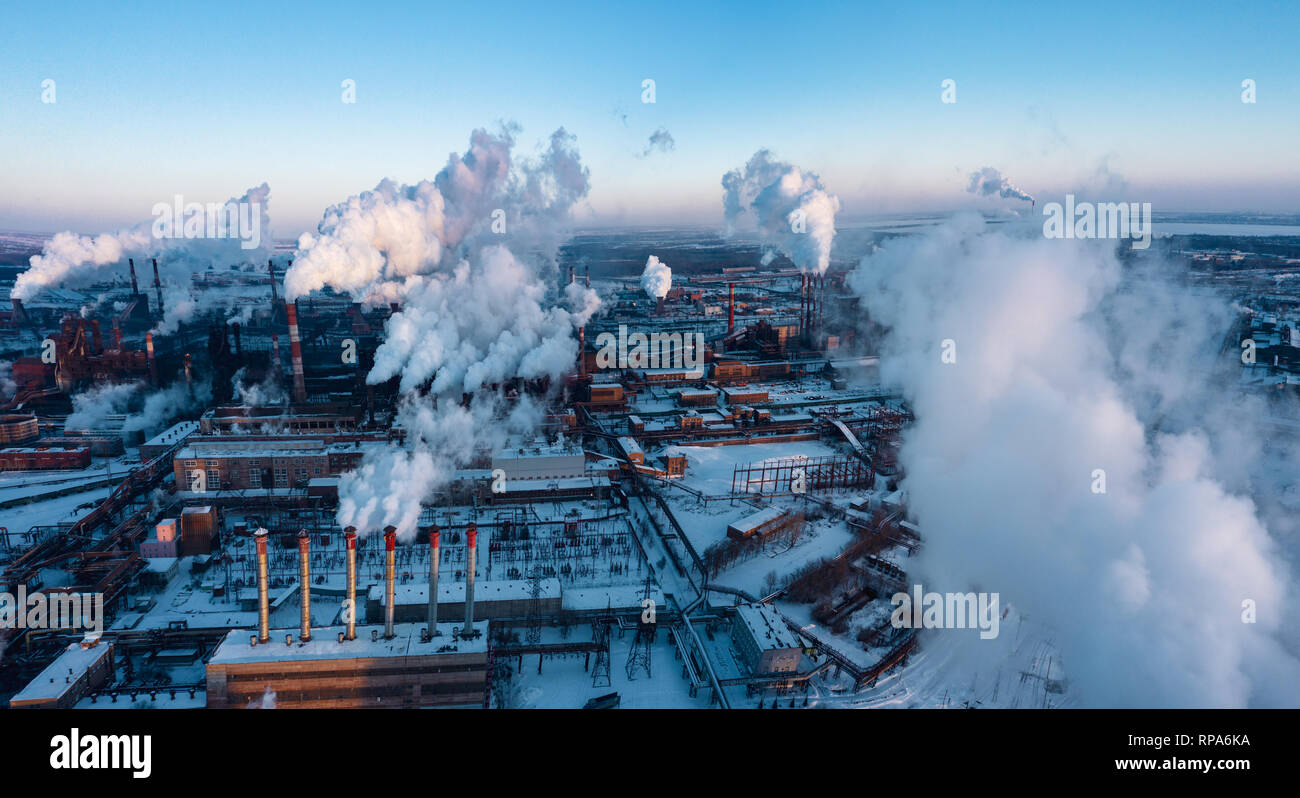 Concetto di inquinamento ambientale, drone vista del tubo ciminiere impianto siderurgico, antenna industriale paesaggio panoramico con cielo blu in inverno sera, Foto Stock