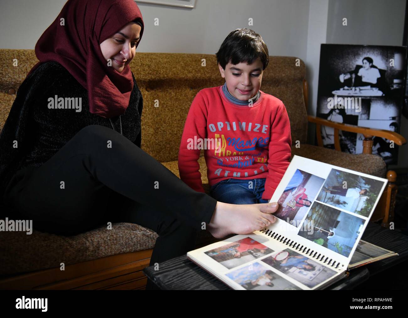Damasco, Siria. Xx Febbraio 2019. Dua al-Bustati, 28, mostra il suo nipote di vecchie foto nella sua casa nel sobborgo di Sehnaya nella campagna di Damasco Capitale della Siria, il 20 febbraio, 2019. Dua al-Bustati nata senza braccia. Tuttavia ella divenne in grado di rompere i limiti con il suo talento di disegno vari dipinti con i suoi piedi. Credito: Ammar Safarjalani/Xinhua/Alamy Live News Foto Stock