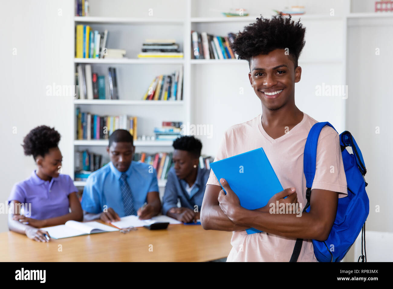 African American giovane adulto studente guardando la fotocamera con la classe a scuola Foto Stock