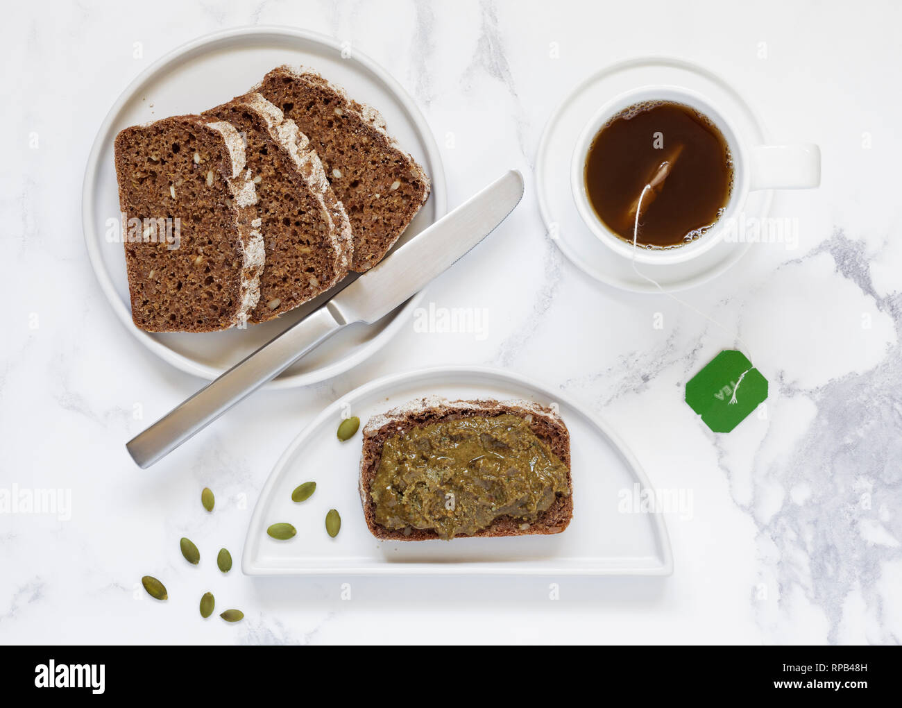 Ryebread affettato e i semi di zucca diffuso con una tazza di tè verde Foto Stock
