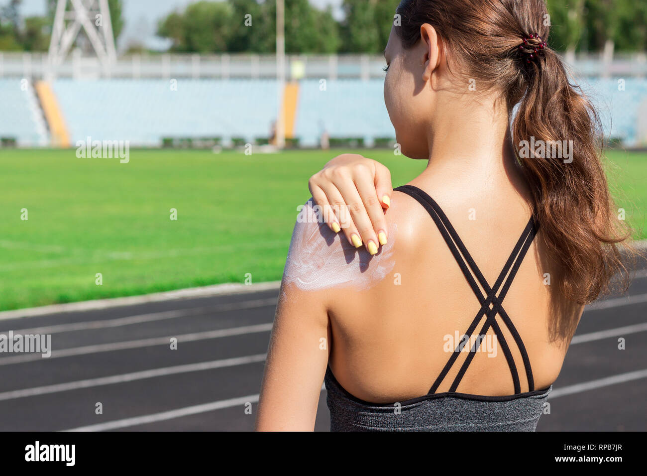 Giovani femmine runner permanente e la messa lozione solare a portata di mano. Ragazza utilizzando sunscream prima di sport in esecuzione esercizio sulle mattine d'estate. Sport e sano Foto Stock