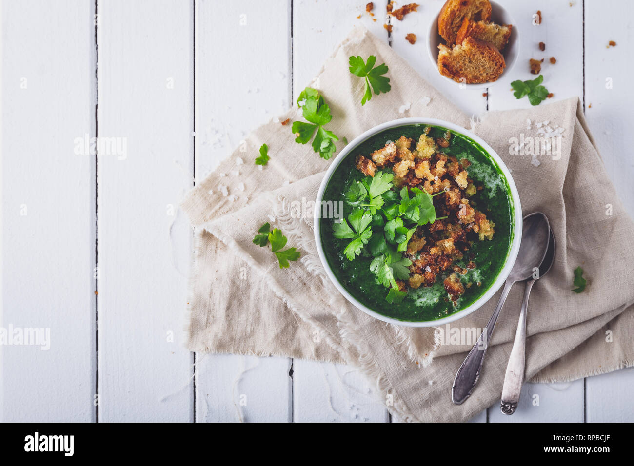 Cremosa zuppa di spinaci con crostoni di pane fresco e prezzemolo, vista dall'alto Foto Stock