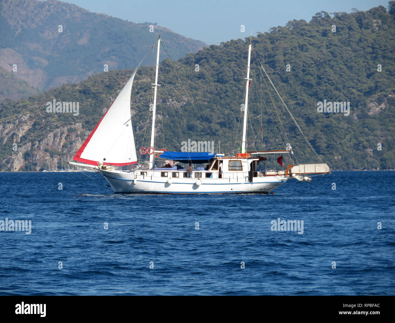 Yacht con i turisti in barca a vela sullo sfondo delle isole di montagna nel mare Egeo. Il pittoresco paesaggio mediterraneo con bianco in barca a vela Foto Stock