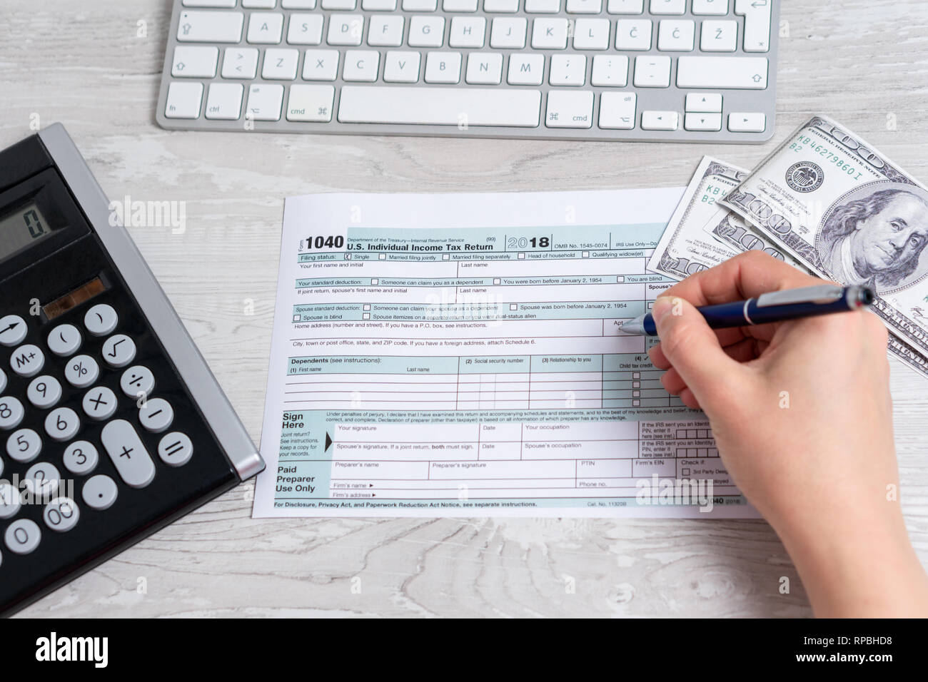 Punto di vista foto di donna e di calcolo e il riempimento di noi sotto forma di imposta accanto alla tastiera del computer, le fatture del dollaro e forma fiscale 1040. 15 aprile 2019 giornata fiscale Foto Stock