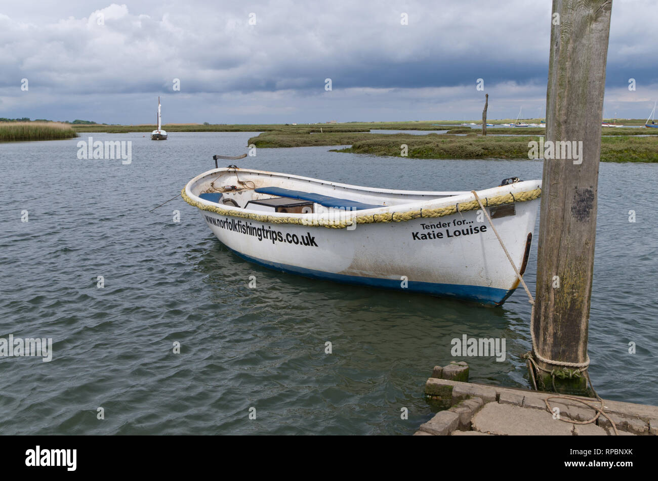 Una solitaria barca ormeggiata su una insenatura di marea a Brancaster Staithe, North Norfolk, Regno Unito Foto Stock