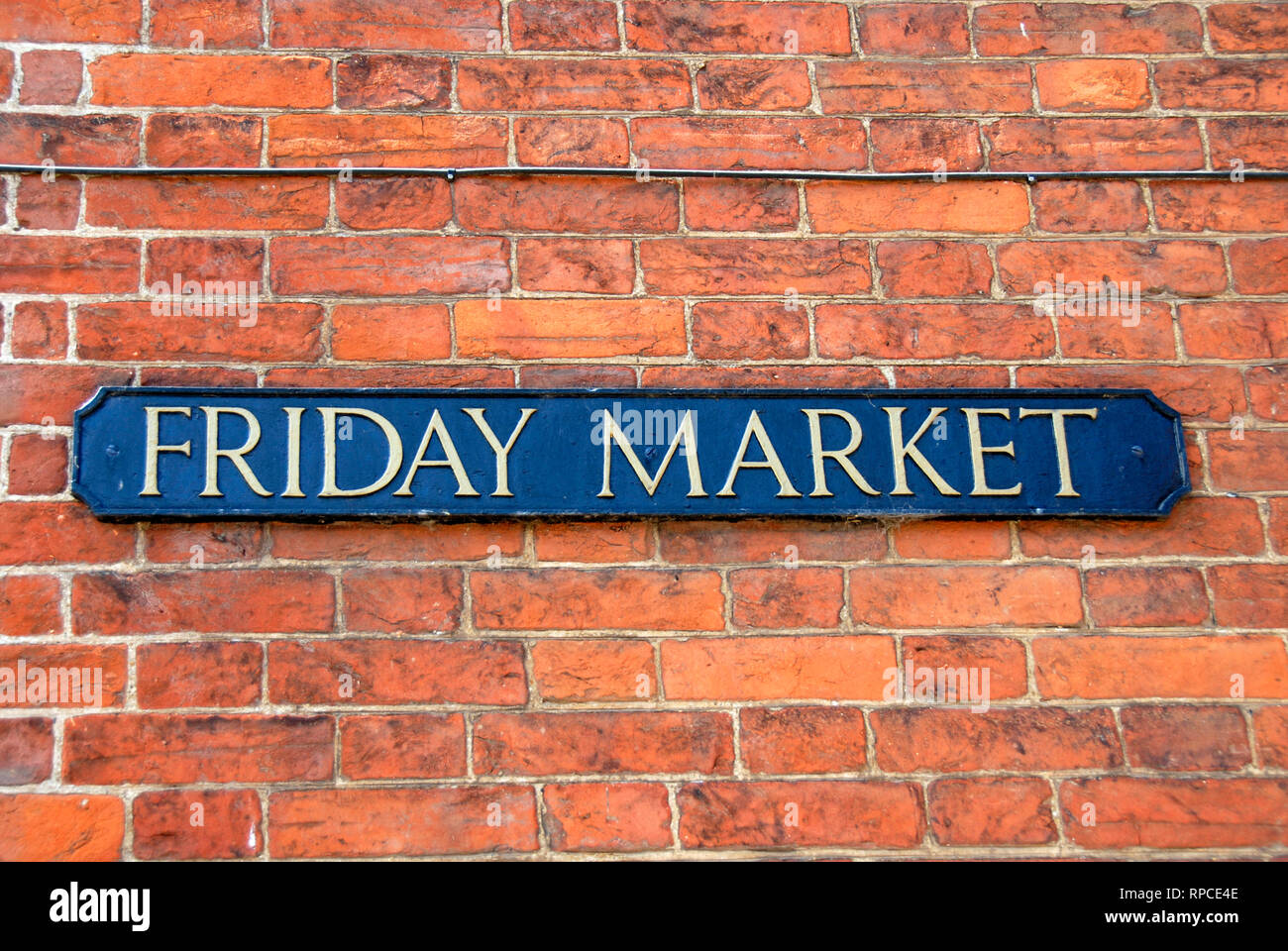 Segno per il nome della strada "Mercato del venerdì" su un muro di mattoni nella comunità rurale. Foto Stock