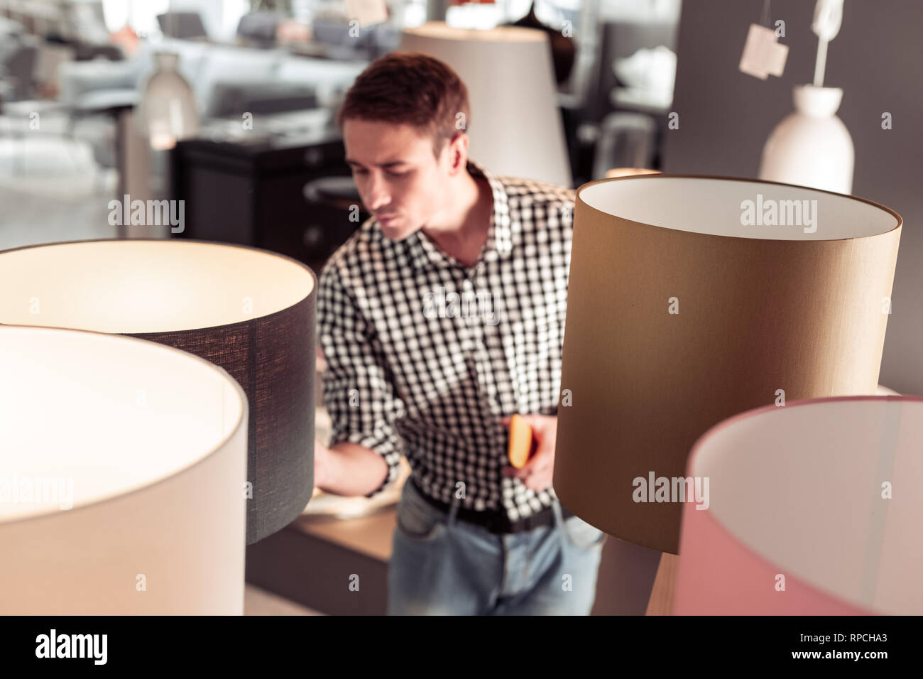 Maschio Tricenarian acquirente attento controllo qualità della lampada in negozio Foto Stock