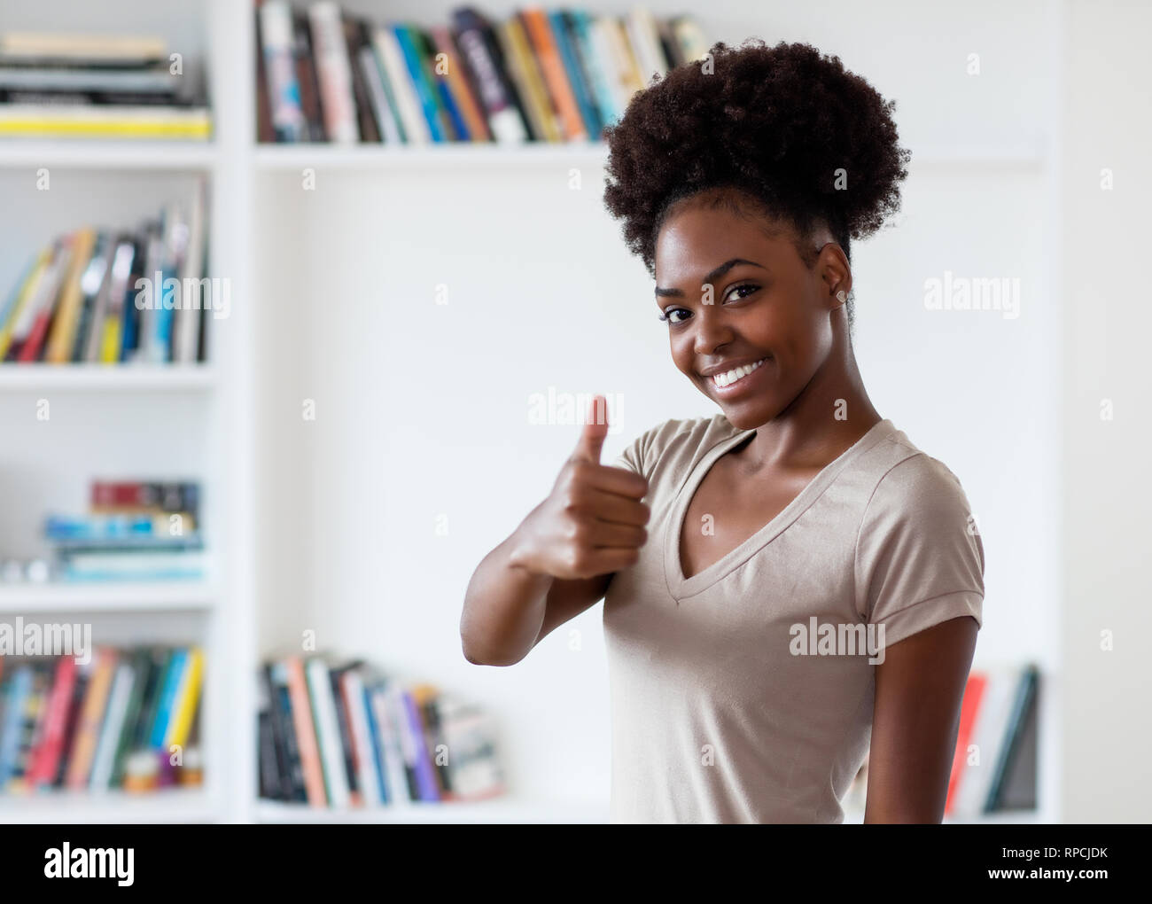 African American giovane donna adulta che mostra il pollice fino al chiuso in casa Foto Stock