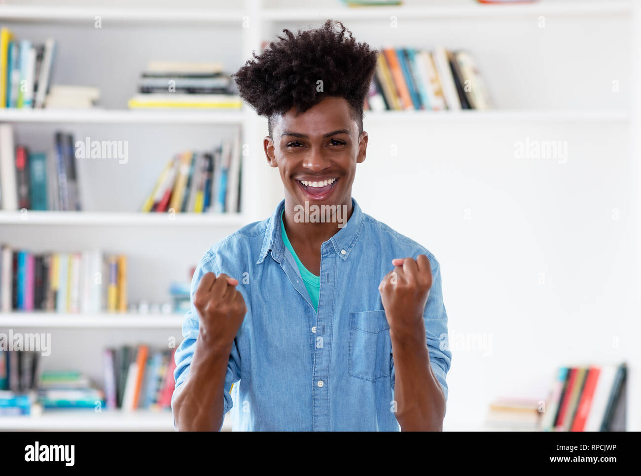 Il tifo americano africano giovane uomo adulto indoor a casa Foto Stock