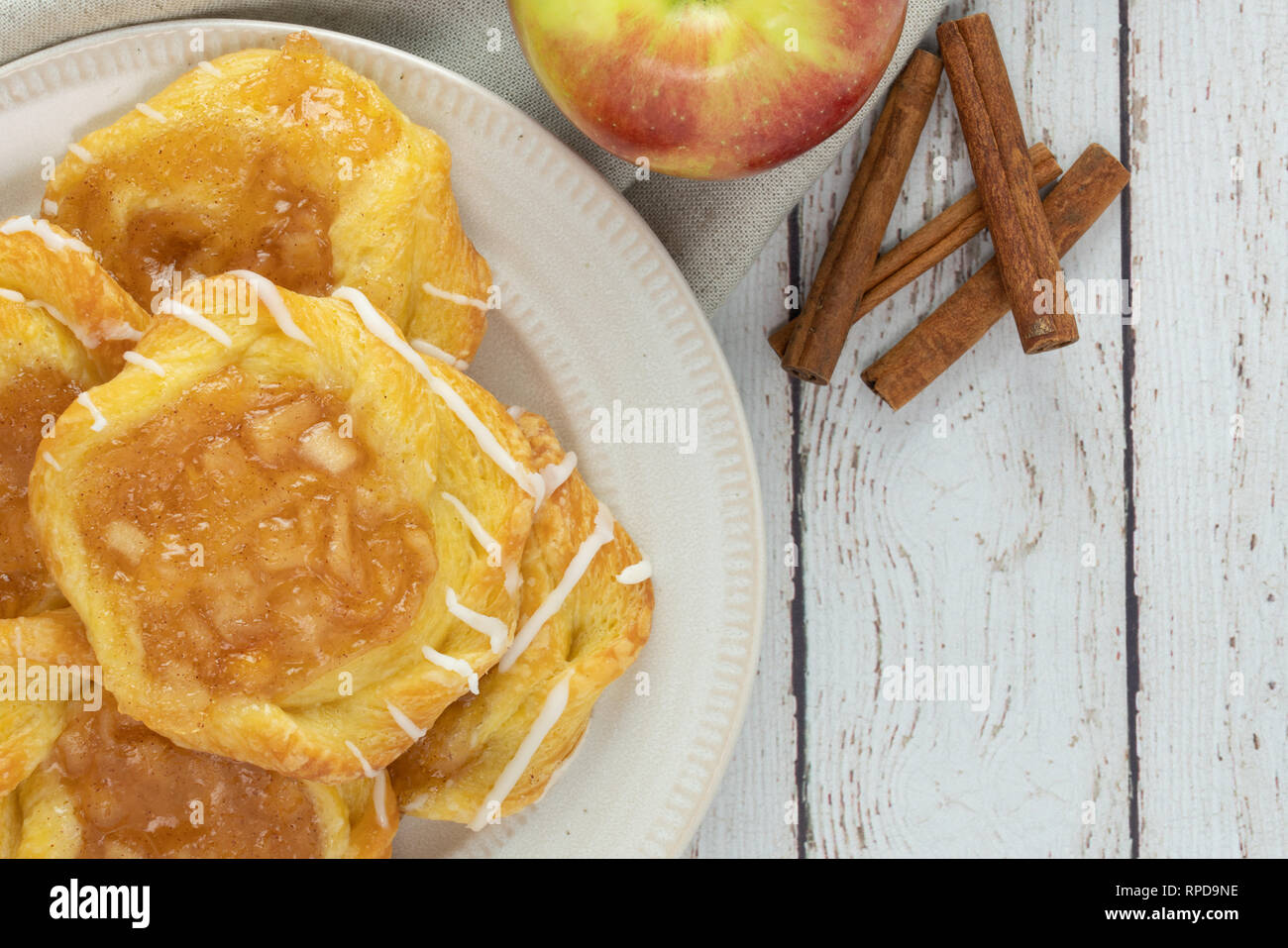 Danese di apple su una piastra con mela e cannella bastoni su un rustico di legno bianco sullo sfondo Foto Stock