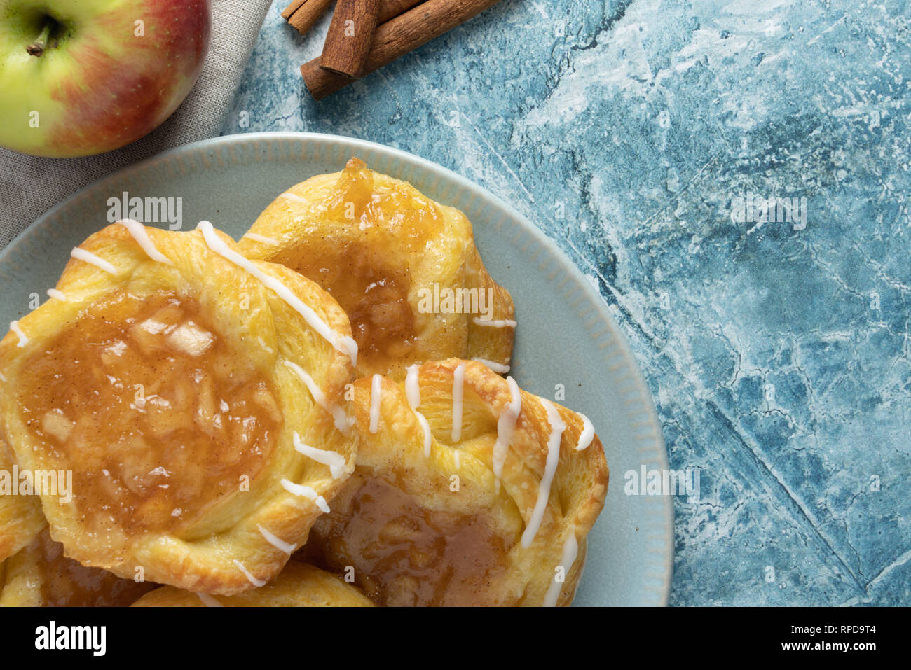 Close up danese di Apple sulla piastra con mela e cannella bastoni su un rustico sfondo blu Foto Stock