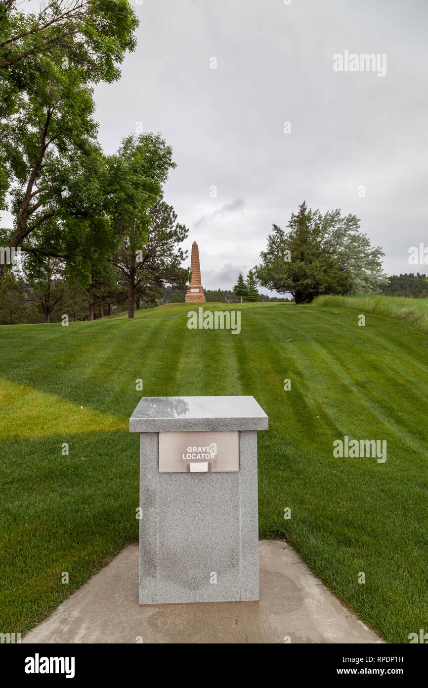 HOT SPRINGS, South Dakota - Giugno 8, 2014: un banco in granito che contiene la tomba locator ledger con un monumento Obelisco in background in primavera calda Foto Stock