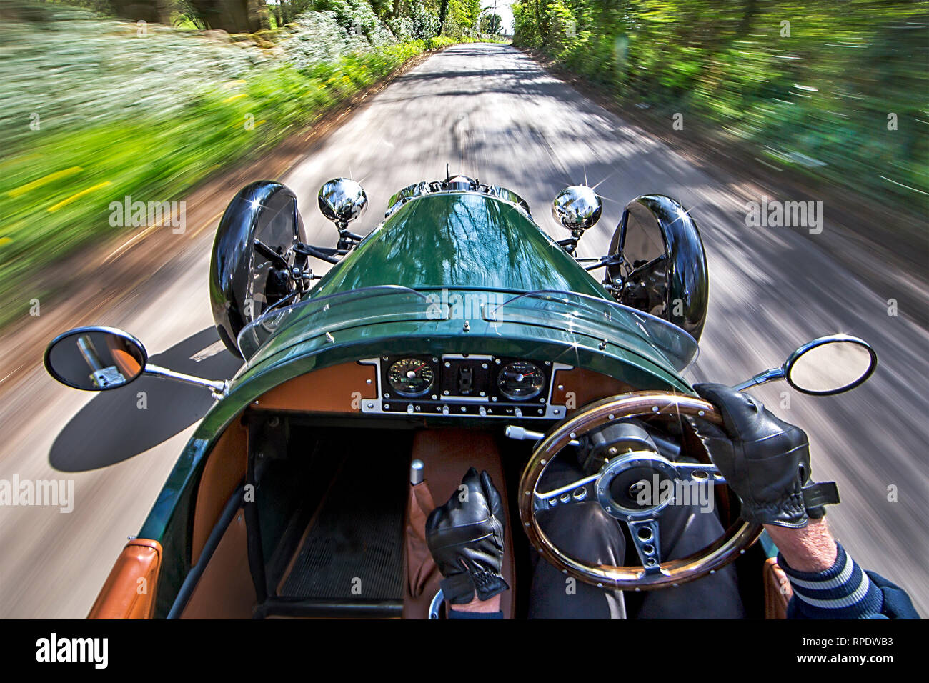 Morgan 3-auto ruota essendo azionato velocemente attraverso un paese di lingua inglese lane con scenario sfocata e un impresion di velocità. Rilasciare firmato. Foto Stock