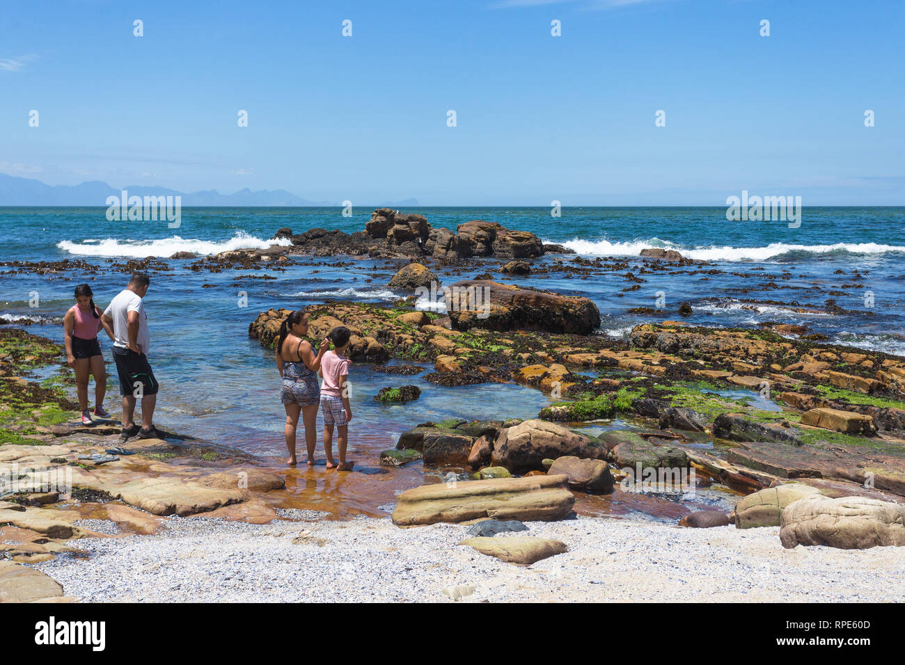 Famiglia sulla spiaggia a bordo delle acque nella Baia di False godendo le vacanze estive e sole a St James beach, Cape Peninsula, Sud Africa Foto Stock