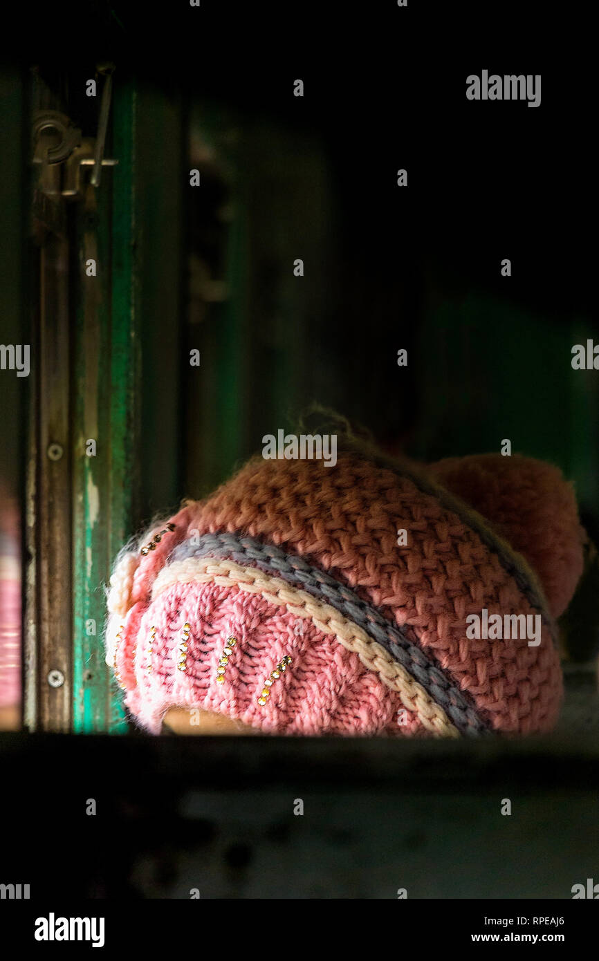 Una donna che indossa una maglia rosa wooly hat guarda fuori dalla finestra di un treno. Foto Stock