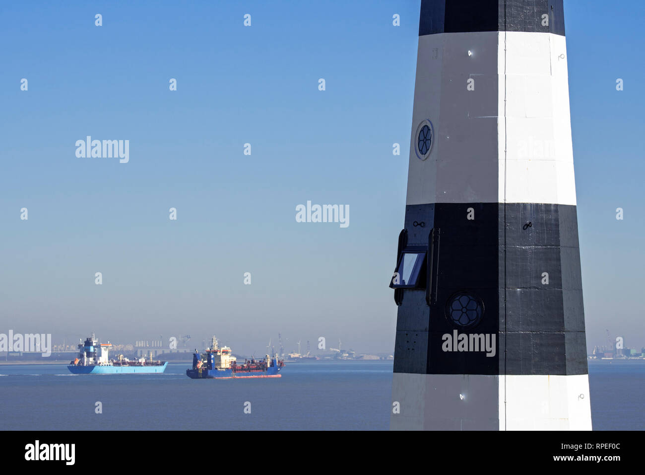 Nieuwe Sluis Lighthouse vicino a Breskens e contenitore / Nave petroliera vela sulla Schelda occidentale di fronte del porto di Vlissingen, Zeeland, Paesi Bassi Foto Stock
