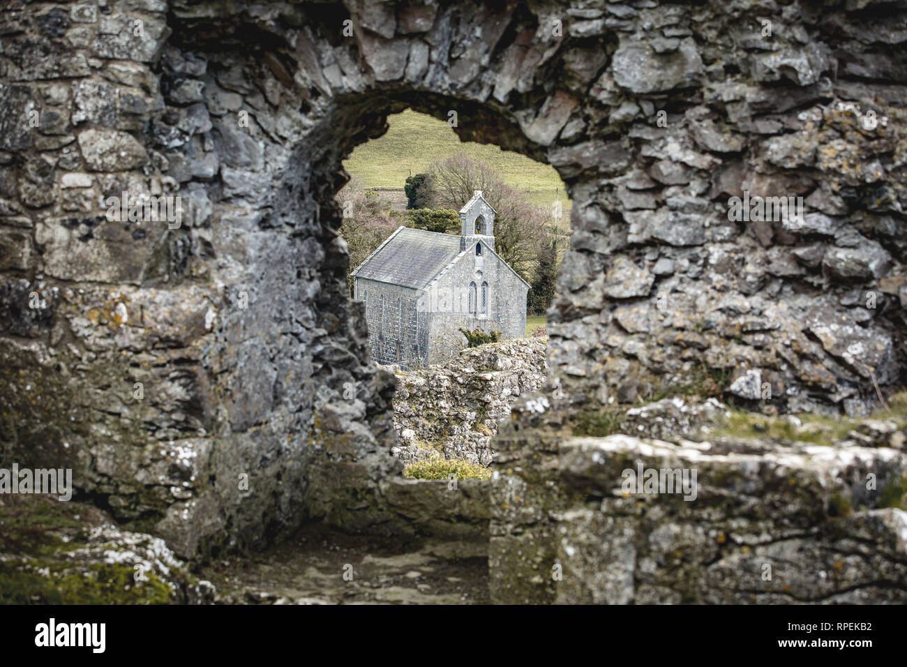 Una piccola chiesa che si vede attraverso il foro nella parete di roccia di Dunamase, nella contea di Laois in Irlanda Foto Stock