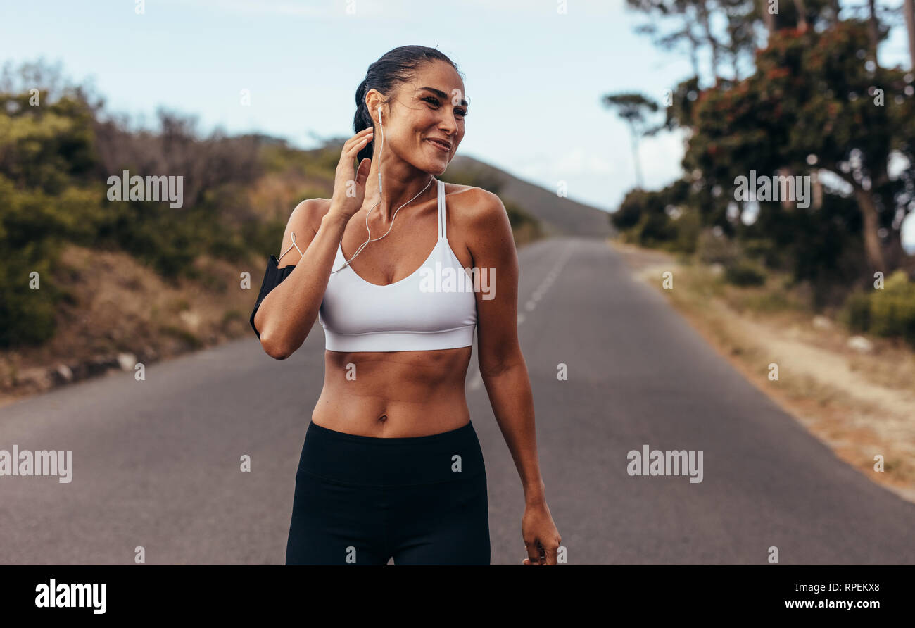 Femmina sportivo outdoor permanente nella mattina. Donna fitness nell'abbigliamento sportivo in allenamento mattutino. Foto Stock