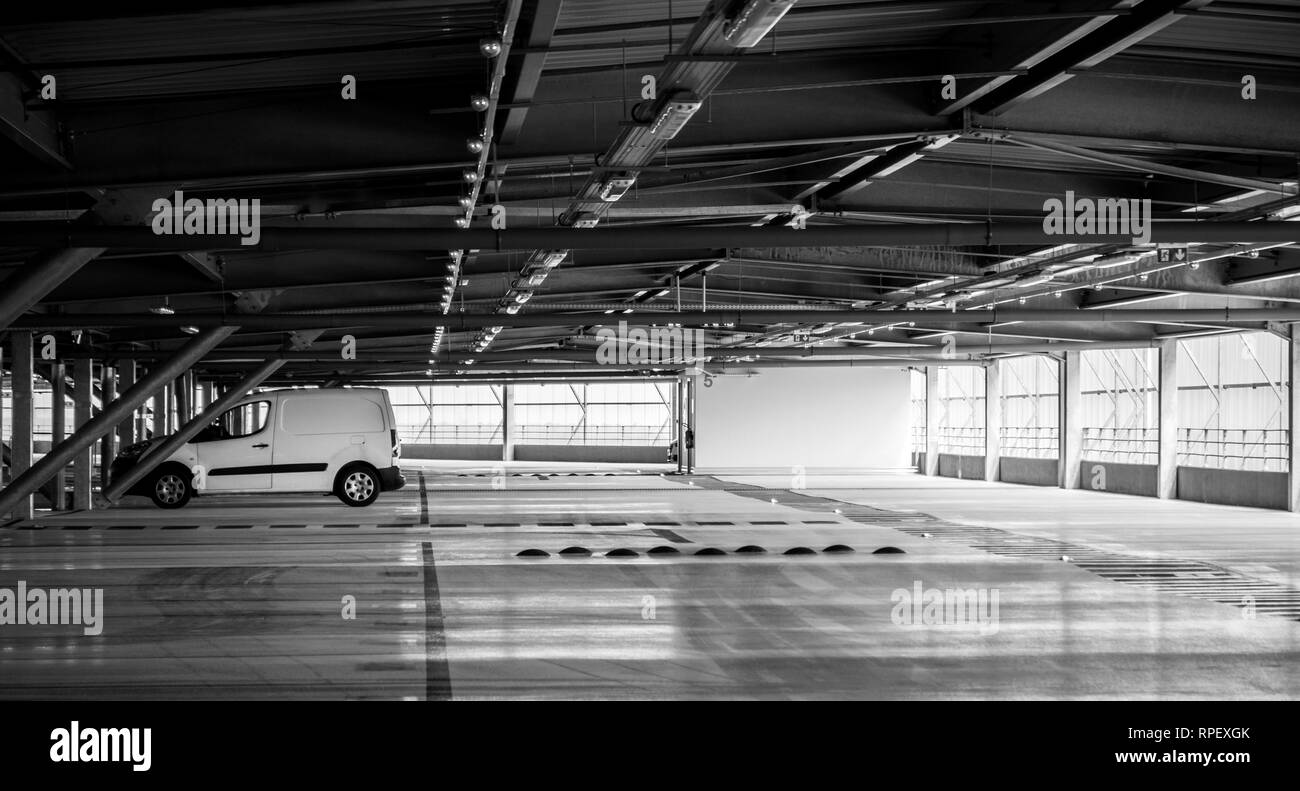 Furgone bianco parcheggiato nel moderno aeroporto Parcheggio - bianco e nero wide image Foto Stock