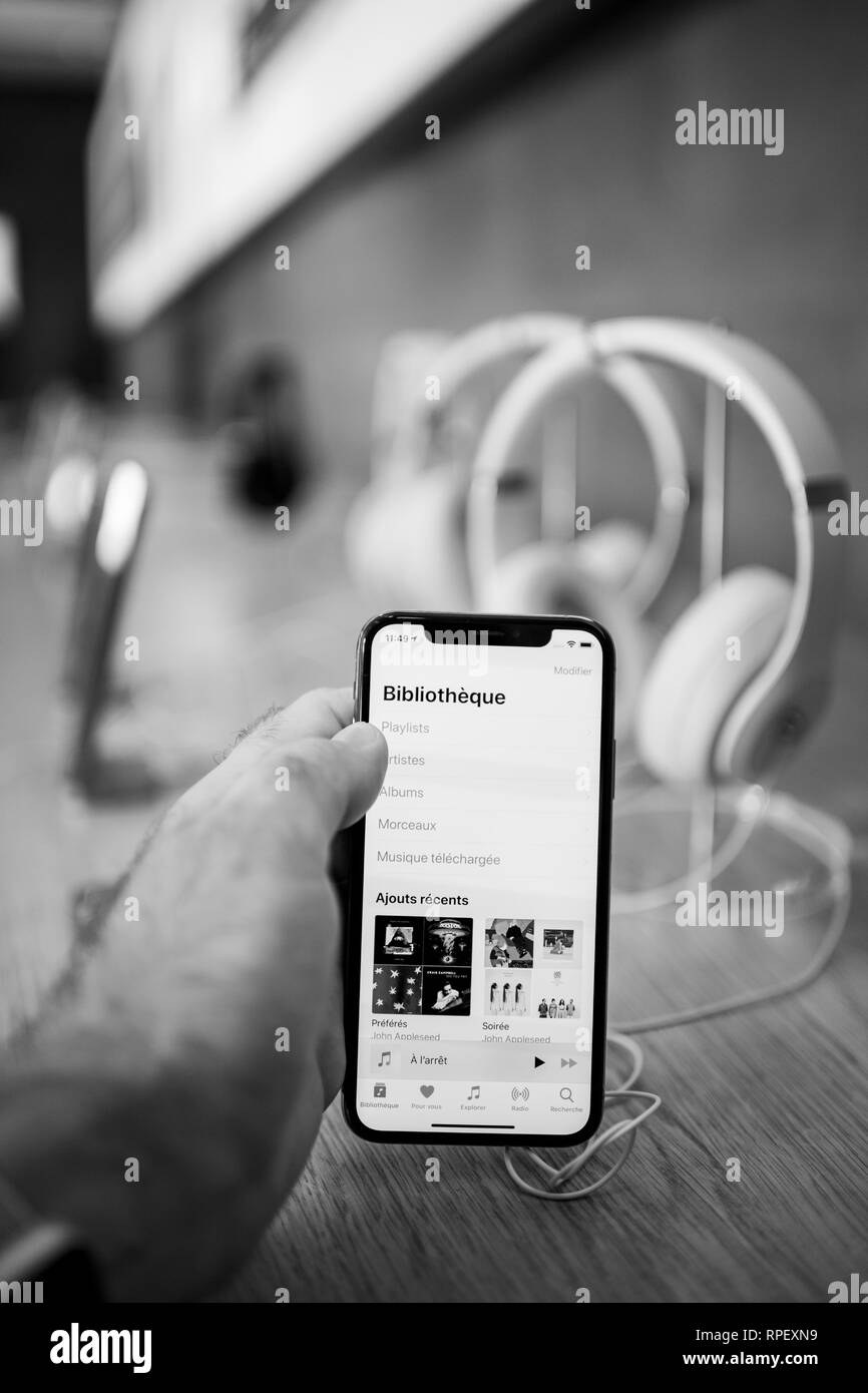 Parigi, Francia - Ott 26, 2018: Man mano che regge il nuovo iphone Xs Xr Max con Apple app Musica e più cuffie wireless bluetooth Beats By Dr Dre Studio 3 in bianco e nero Foto Stock