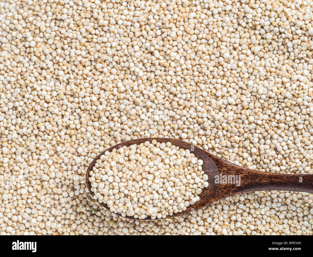 Grano di quinoa. Non cotti materie la quinoa come sfondo. Vista dall'alto di quinoa con grani in cucchiaio di legno. Copia dello spazio. Foto Stock