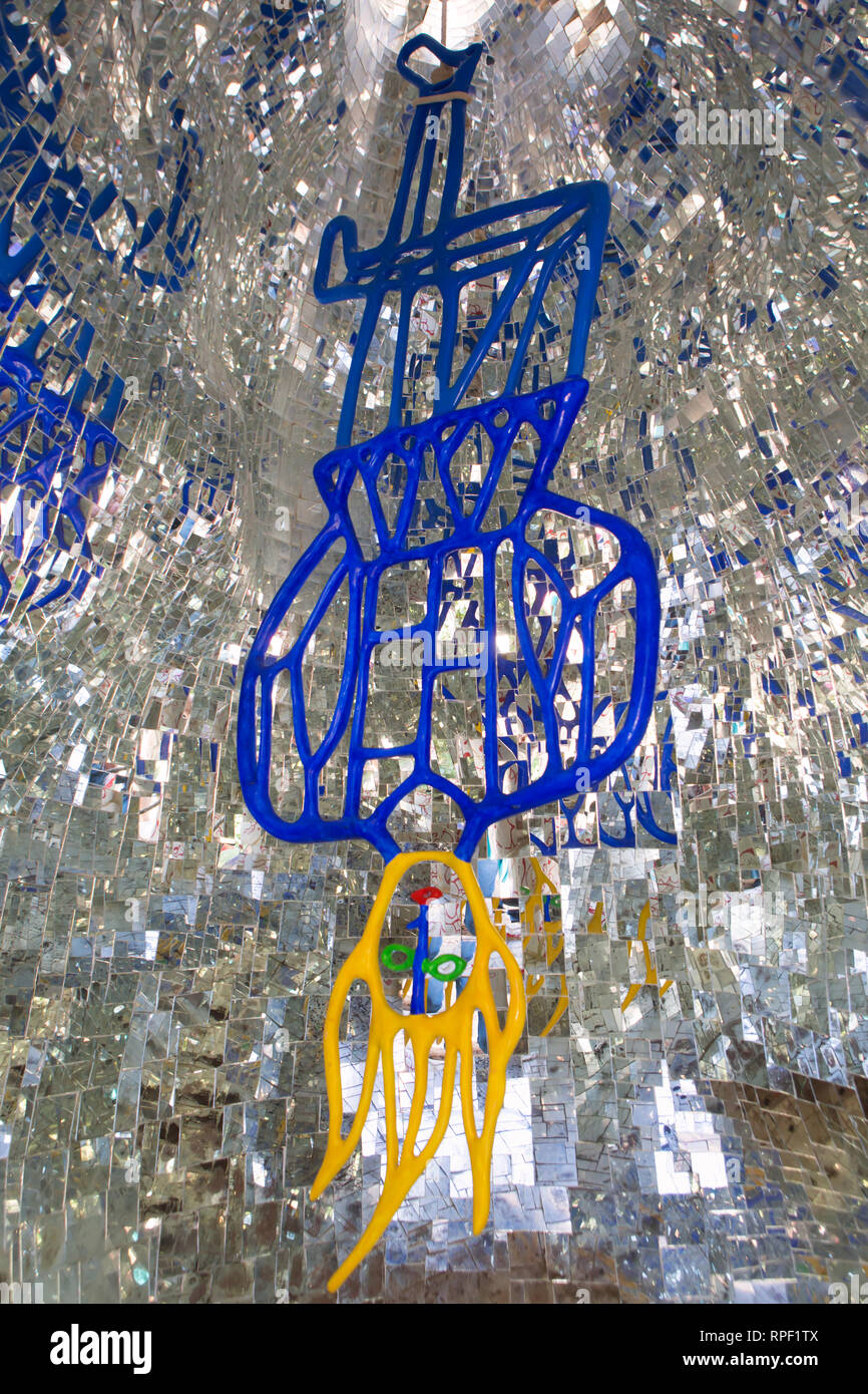 La scultura di un uomo appeso a testa in giù che raffigura l'impiccato dal mazzo di Tarocchi. Il giardino di sculture è stato creato da Niki de Saint Phalle. Foto Stock