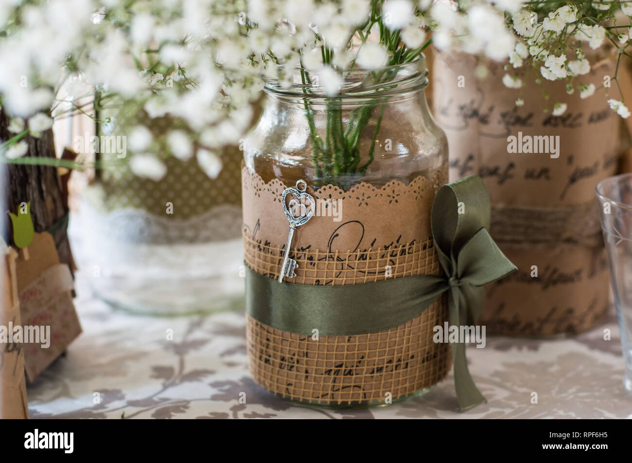 Decorazioni per matrimoni per la tavola, fiori bianchi nel vasetto di vetro, piastra sul primo piano, chiave come un elemento di design Foto Stock