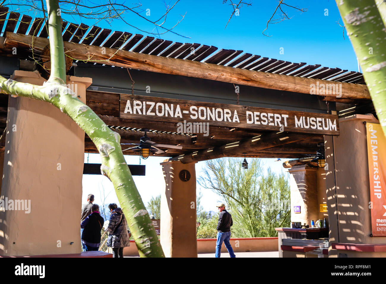 I visitatori di passeggiare sotto il rustico intagliati a mano cartello in legno appeso sopra l'entrata dell'Arizona-Sonora Desert Museum di Tucson, AZ Foto Stock