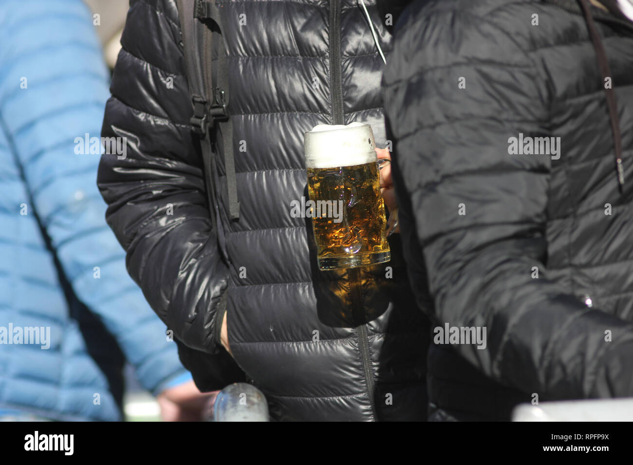 Persone allineando per una fresca birra tedesca a inizio primavera. Sun è la formazione di macchie la scena e fa sì che il liquido splendente. Foto Stock