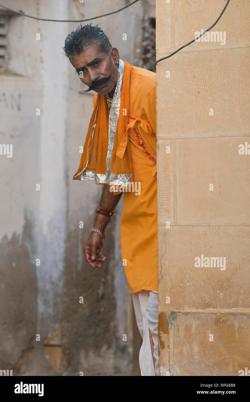 Uomo in abito tradizionale spiata da dietro un muro, Jaisalmer, Rajasthan, India Foto Stock