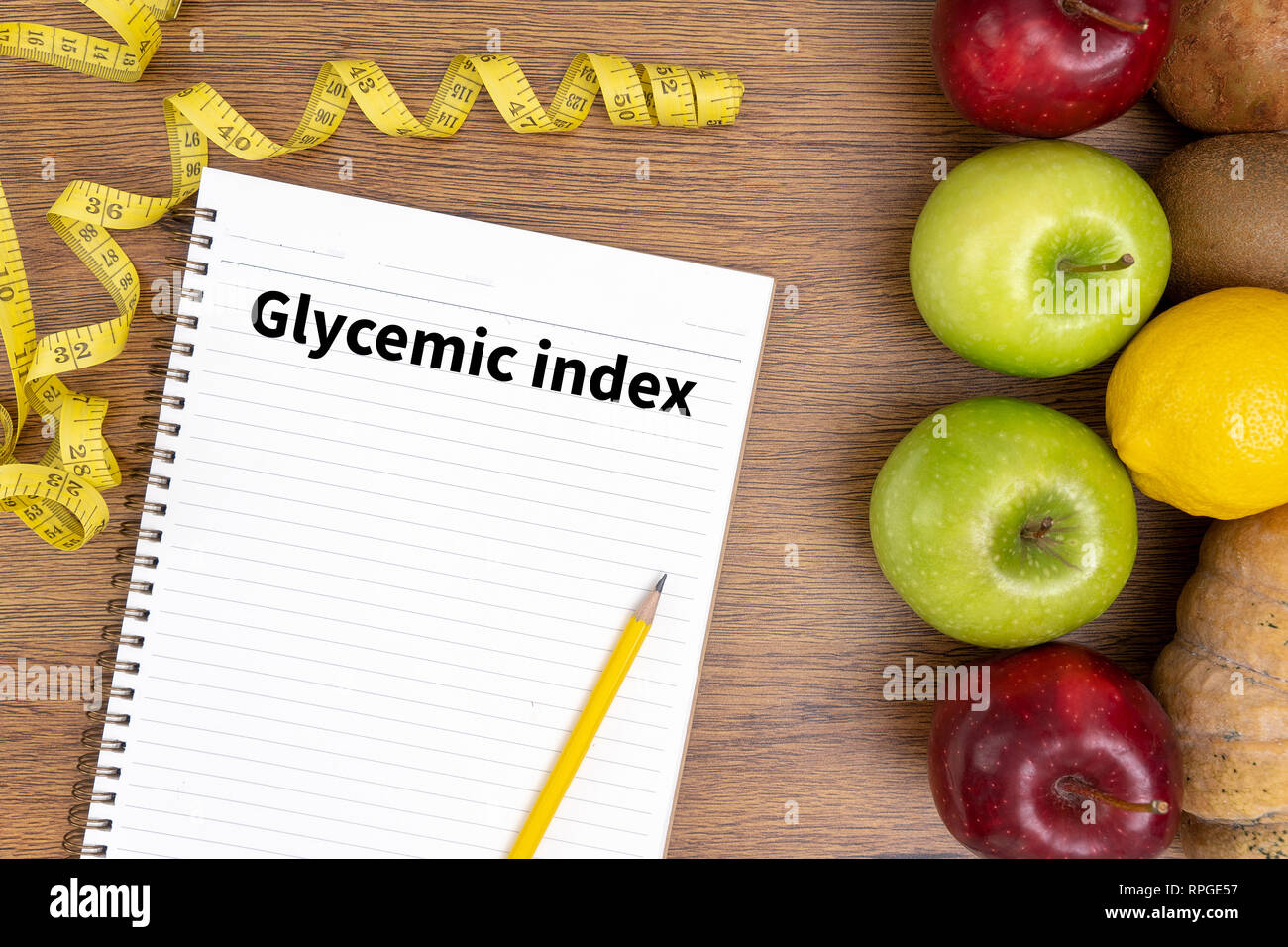 Indice Glicemico Fitness e perdita di peso concetto, manubri, bianco scala, frutta e nastro di misurazione su un tavolo di legno, vista dall'alto Foto Stock