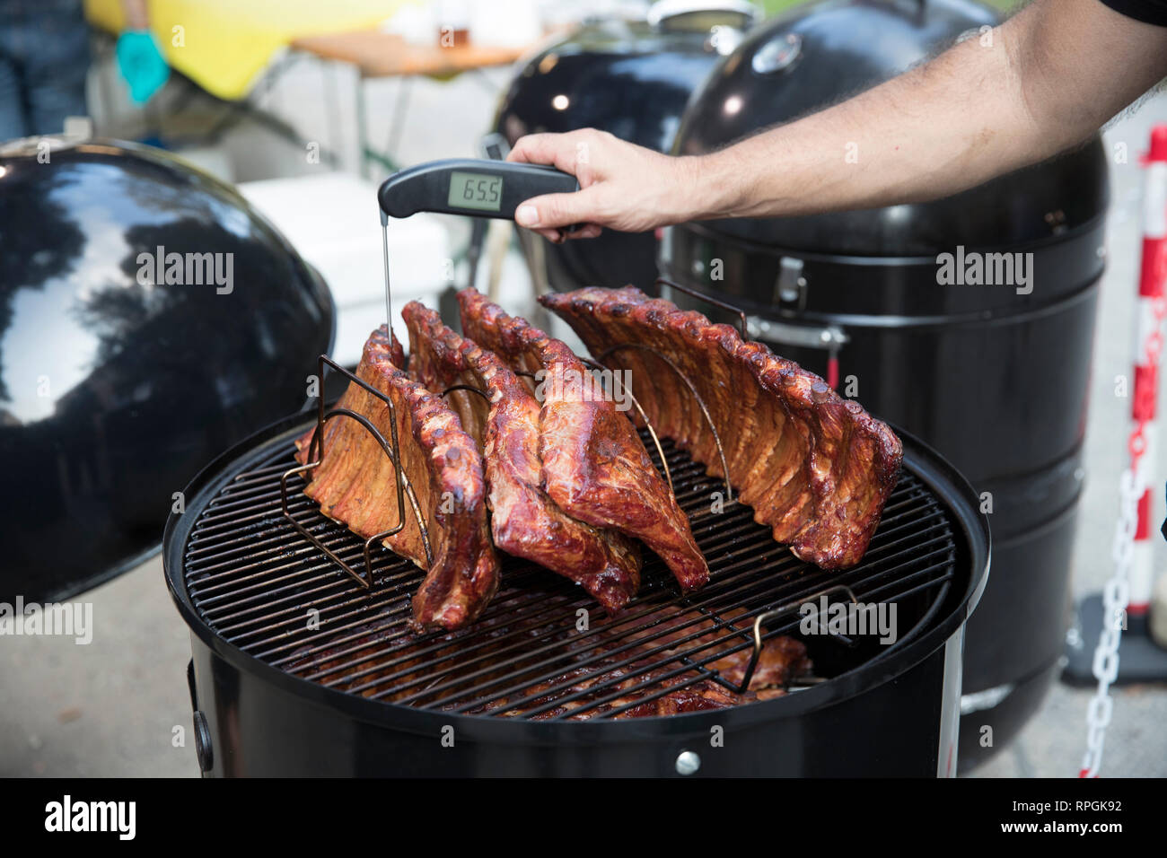 Primo piano di un uomo misurando la temperatura della carne sul barbecue. Foto Stock