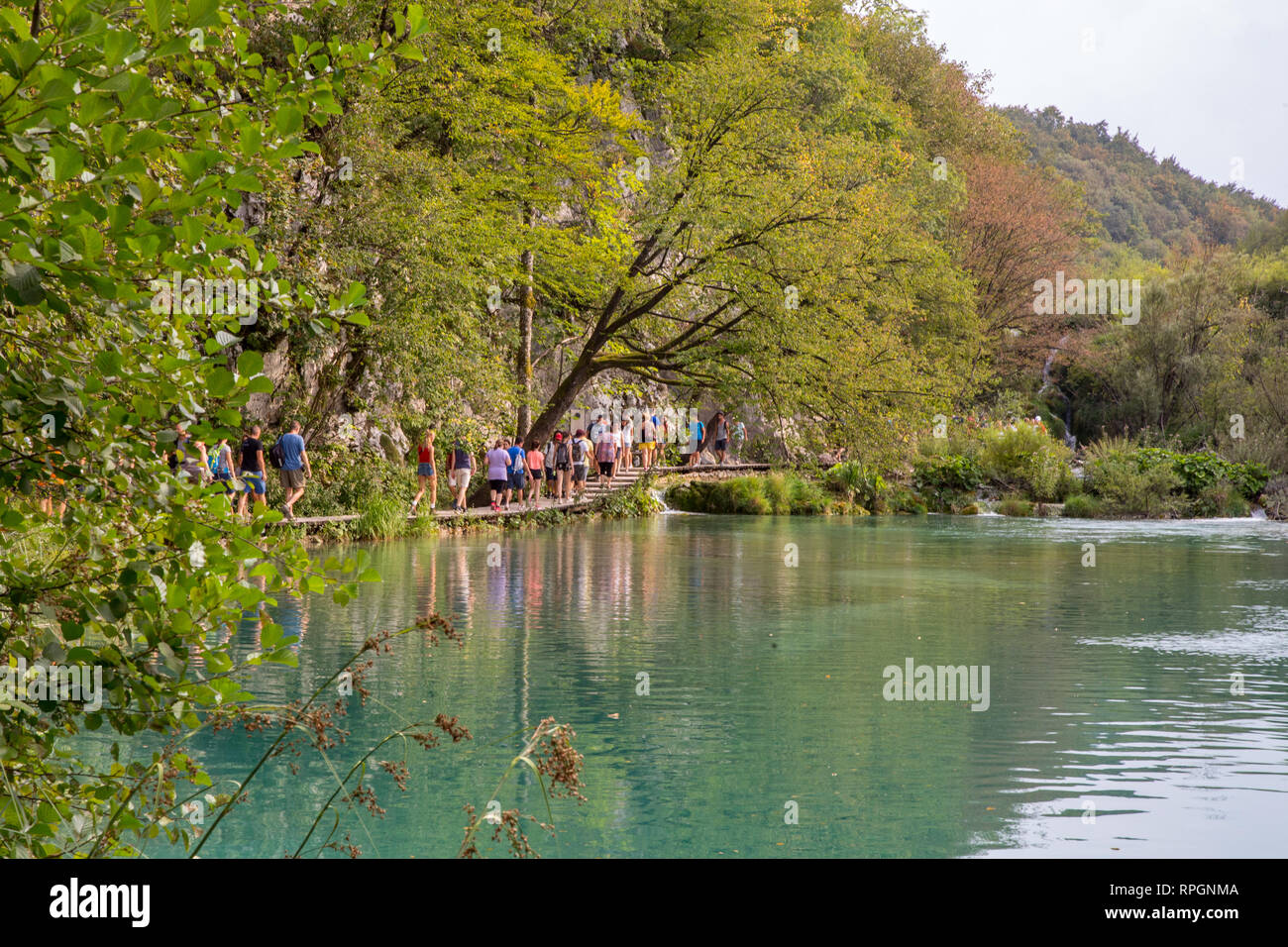 I visitatori potranno gustarsi la passeggiata lungo il percorso di legno sul lato di uno dei laghi di Plitvice in Croazia. Foto Stock