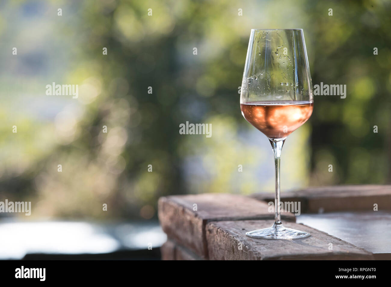 Outdoor inquadratura orizzontale al tramonto, un elegante bicchiere di vino rosè. soggetto e concentrarsi sulla destra Foto Stock