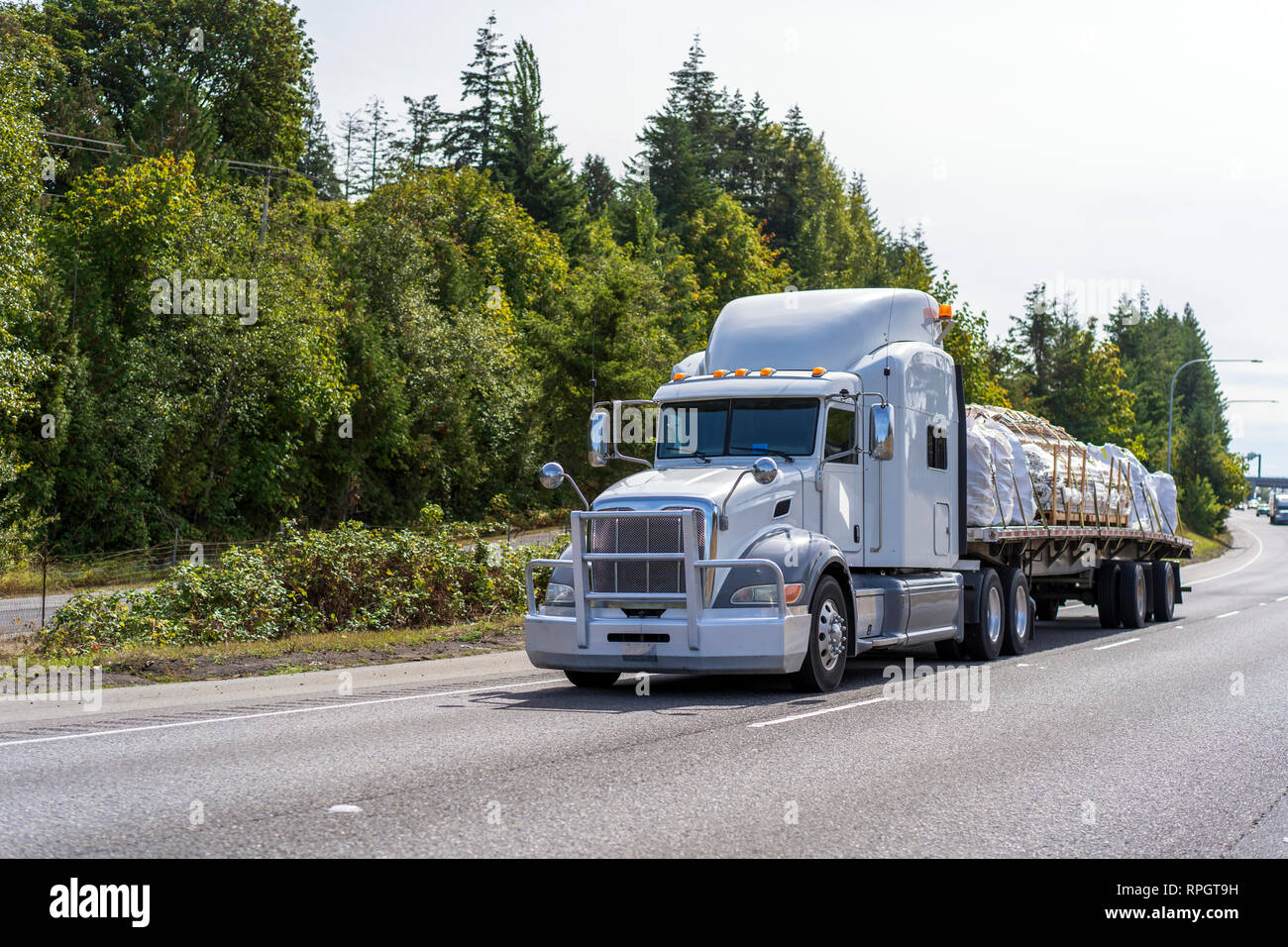 Big Rig grigio chiaro classici americani del cofano del trasporto a lungo raggio semi aerodinamica carrello con griglia in alluminio guard il trasporto commerciale cargo su appartamento b Foto Stock