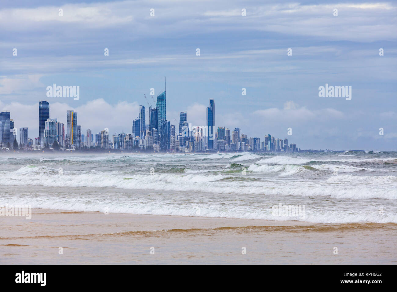 Oceano onde provenienti sulla riva con Gold Coast City grattacieli in background Foto Stock