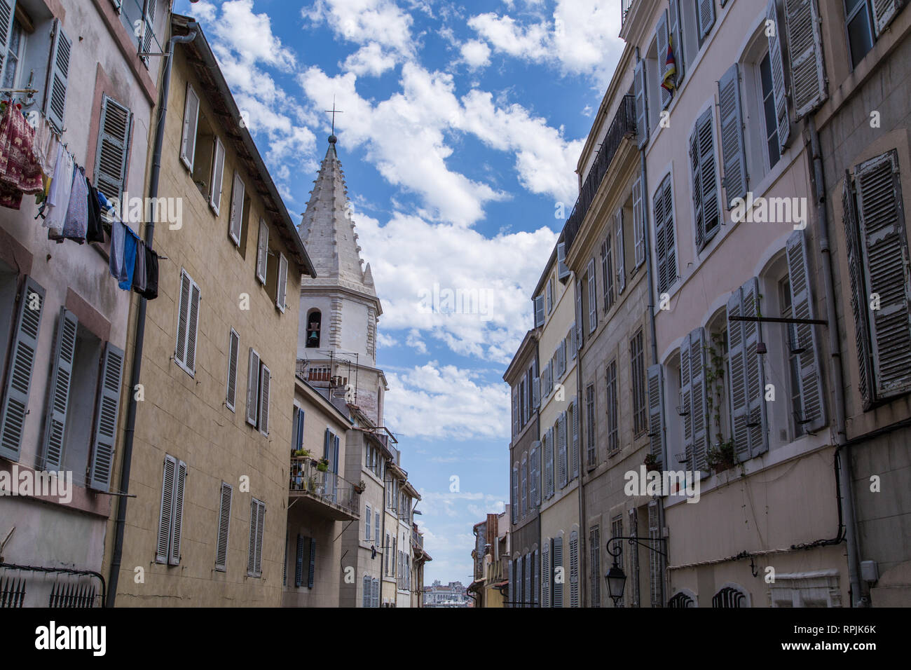 Una skyline di case color pastello con bellissime imposte linea un grazioso vicolo del vecchio porto di Marsiglia, Francia, in una bella giornata di primavera. Foto Stock