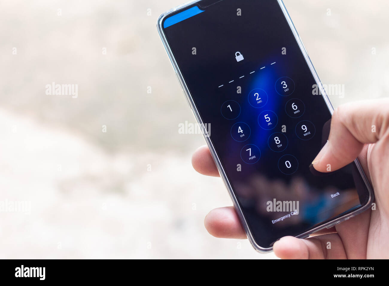 Mano azienda smartphone durante l'immissione del codice. Foto Stock