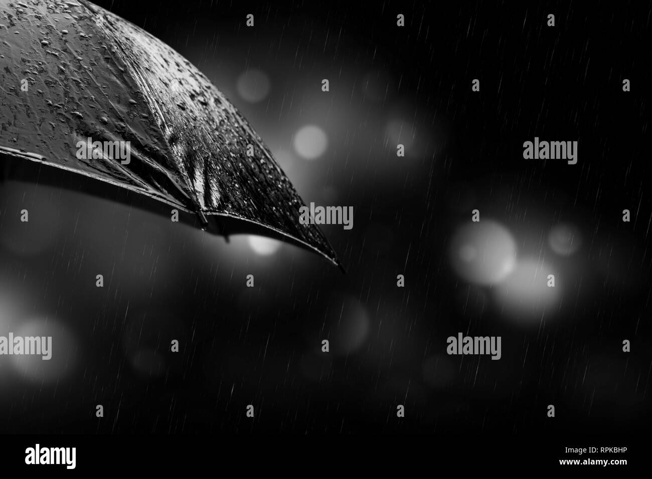 Gocce di pioggia da un ombrello nero concept per il maltempo su sfondo di notte Foto Stock