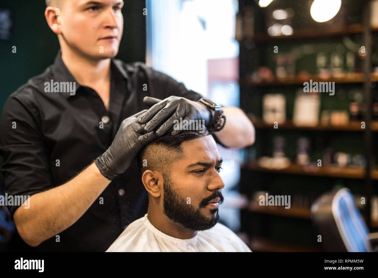 Uomo Barbuto con barba lunga e brutale, parigamba indiano con i baffi, con capelli alla moda, haircut, ottenendo polvere sulla pelle con make up pennello da barbiere o Foto Stock