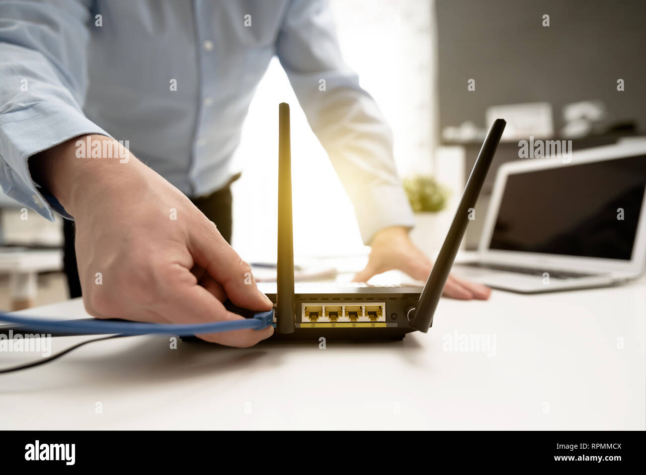 L uomo si connette il cavo internet al router di presa. Veloce e accesso wireless a internet concept Foto Stock