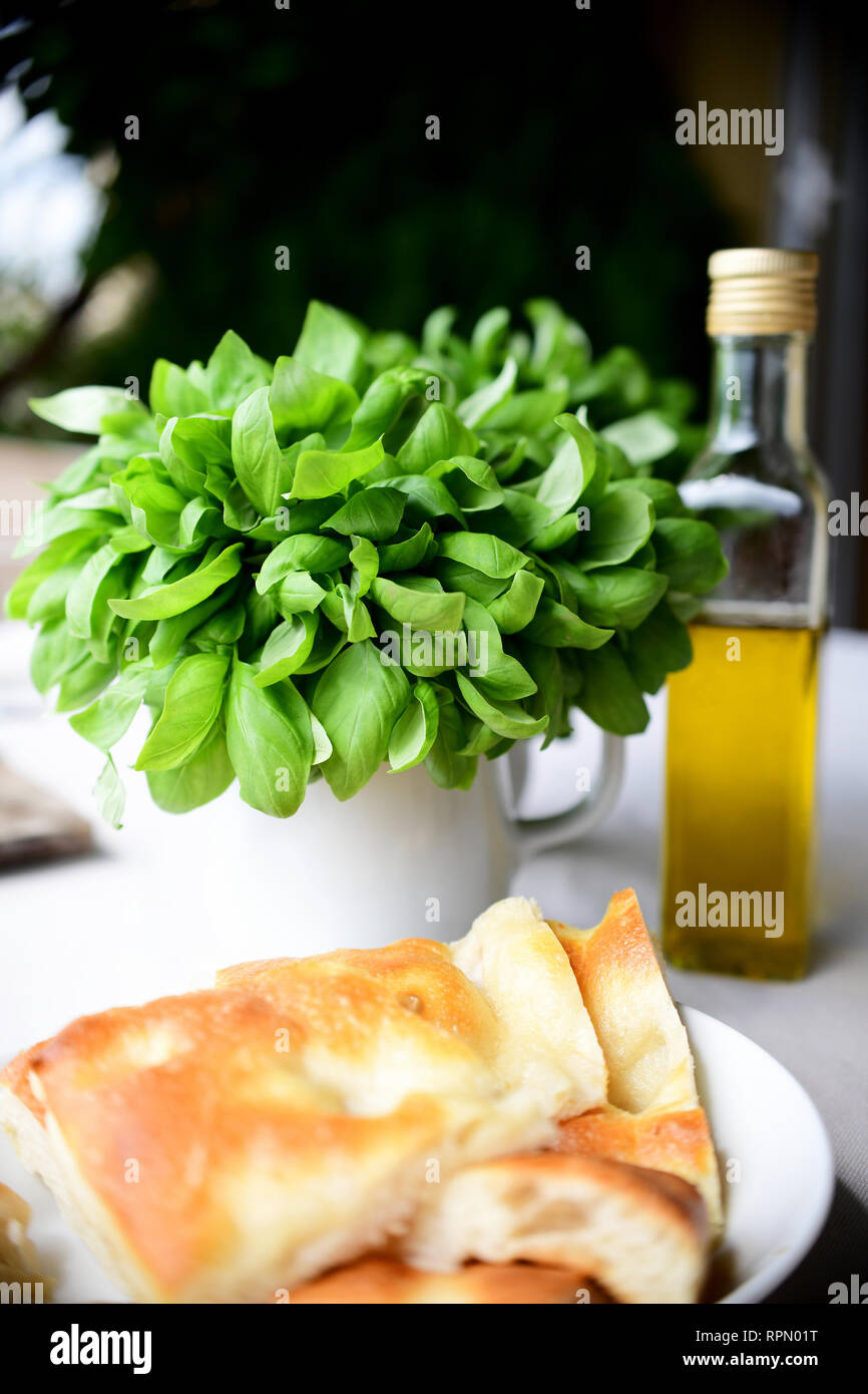 La DOP Fresca basilico genovese, una bottiglia di olio extra vergine di oliva e e la tradizionale focaccia, tre elementi essenziali della dieta genovese Foto Stock