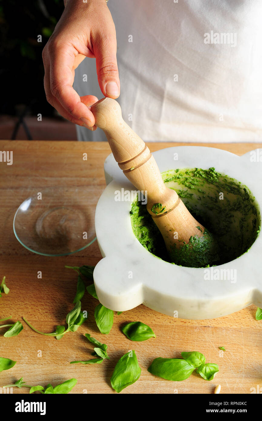 Tradizionale mortaio e pestello pesto rendendo con fresco DOP basilico genovese. Foto Stock