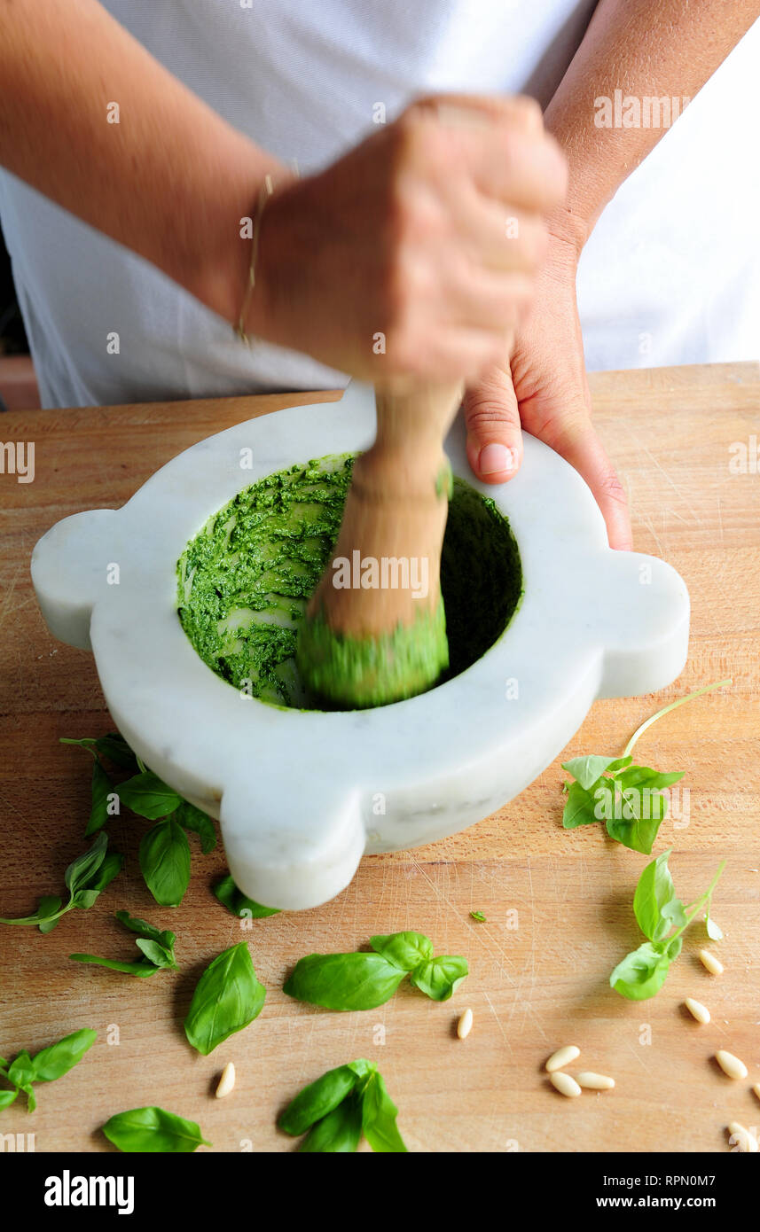 Tradizionale mortaio e pestello pesto rendendo con fresco DOP basilico genovese. Foto Stock