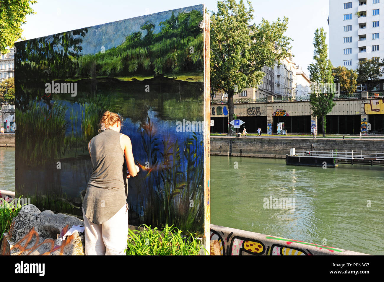 Artista ucraino Anja Filatova pulisce una delle sue opere lungo il Donaukanal, Vienna, Austria Foto Stock