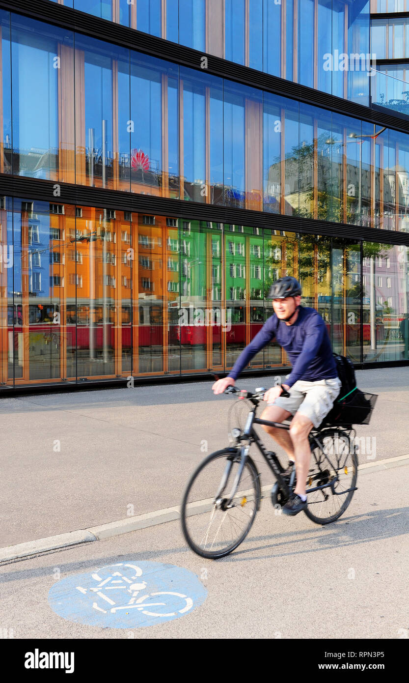 Uomo in sella ad una bicicletta di fronte ad uno dei recentemente terminato edifici del campus di Erste, Vienna, Austria Foto Stock